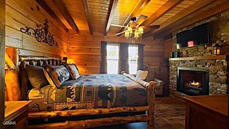 710 Village Loop Rd, Gatlinburg, TN 37738 - bedroom with wooden ceiling with exposed beams, a stone fireplace, and wood walls