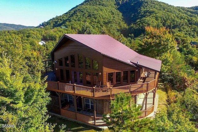 back of property featuring a forest view and a deck with mountain view