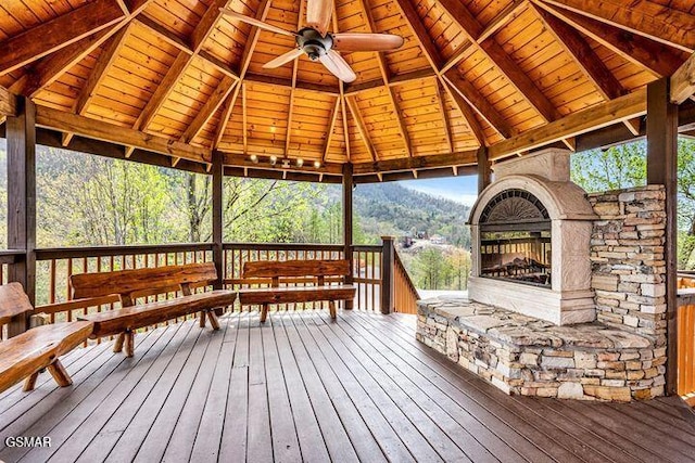 wooden terrace with a gazebo, ceiling fan, and a multi sided fireplace