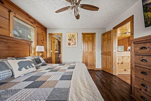 bedroom featuring a ceiling fan, a textured ceiling, wood walls, and wood finished floors