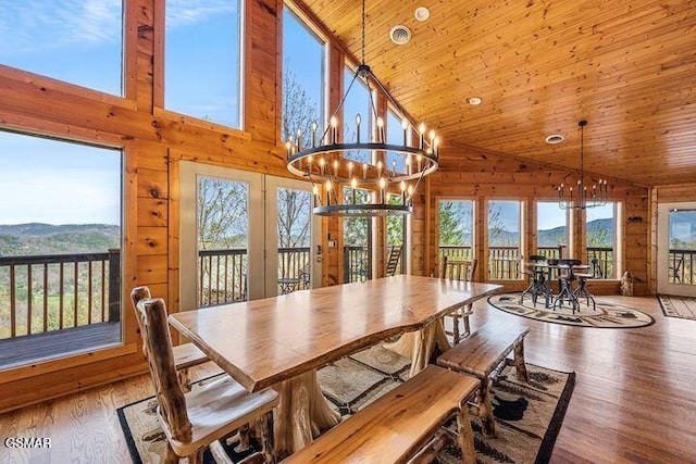 dining area featuring high vaulted ceiling, wood walls, a mountain view, and french doors