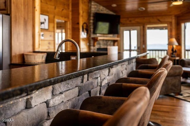 bar featuring wood ceiling, wood walls, wood finished floors, a sink, and freestanding refrigerator
