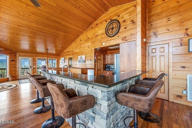 bar featuring wood-type flooring, high vaulted ceiling, wood walls, and wooden ceiling