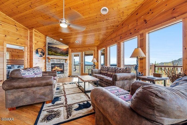 living area with visible vents, wood walls, wood finished floors, ceiling fan, and vaulted ceiling
