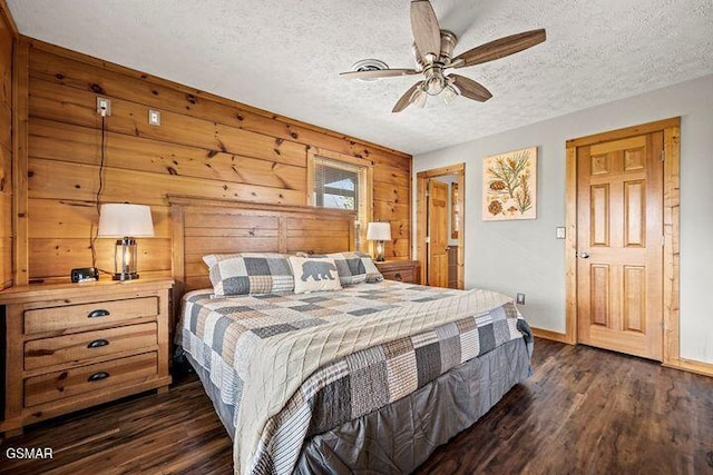 bedroom featuring ceiling fan, a textured ceiling, baseboards, wooden walls, and dark wood-type flooring