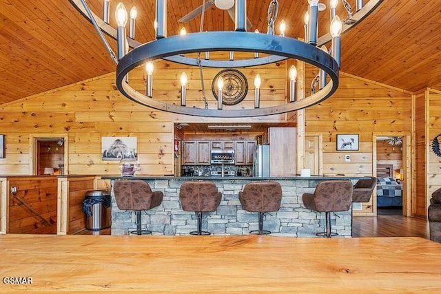 kitchen featuring wooden walls, stainless steel appliances, high vaulted ceiling, and wooden ceiling