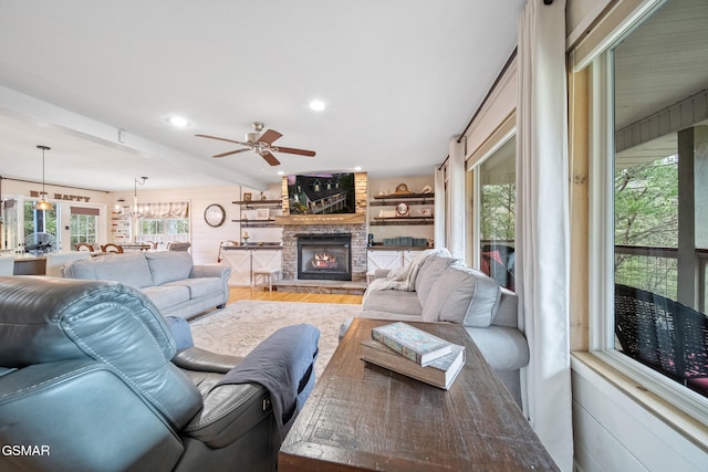 living area featuring wood finished floors, ceiling fan, a healthy amount of sunlight, and a fireplace