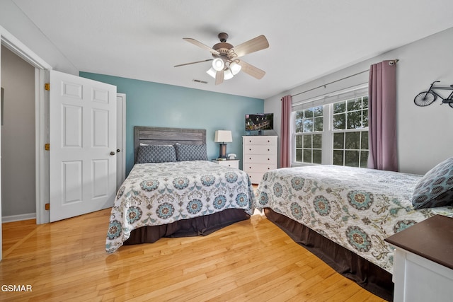 bedroom featuring visible vents, a ceiling fan, baseboards, and wood finished floors