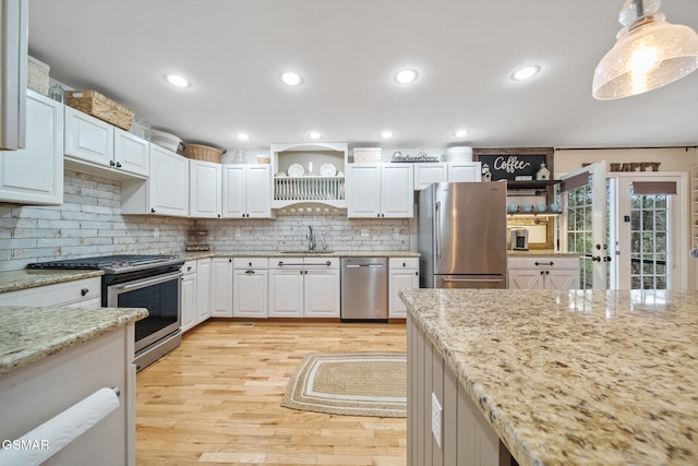 kitchen featuring open shelves, appliances with stainless steel finishes, a sink, and light wood-style floors