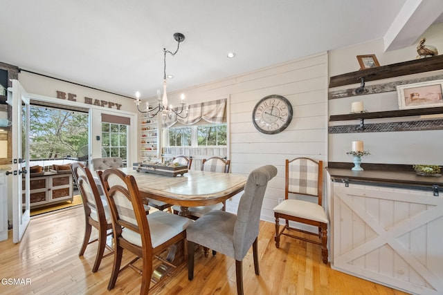 dining room featuring an inviting chandelier, recessed lighting, light wood-style floors, and wooden walls