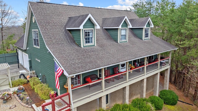 rear view of property featuring a shingled roof, fence, and a balcony