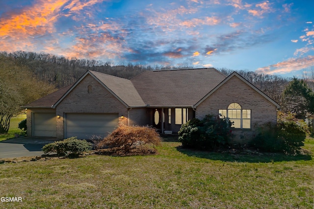 view of front of home featuring a front yard, brick siding, concrete driveway, and an attached garage