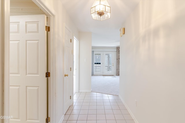 hallway with light tile patterned floors, light colored carpet, baseboards, and french doors