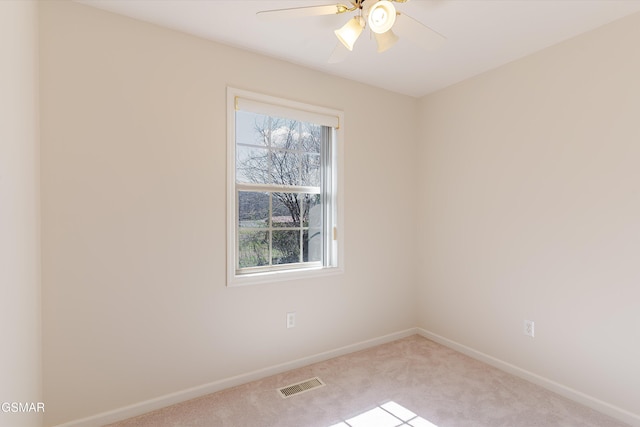 carpeted spare room with visible vents, a ceiling fan, and baseboards