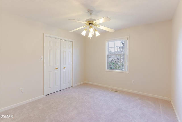 unfurnished bedroom featuring visible vents, baseboards, a closet, and light carpet