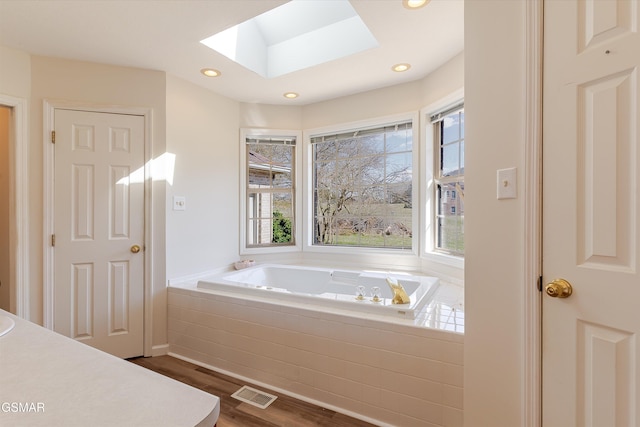 bathroom with visible vents, recessed lighting, a skylight, wood finished floors, and a bath