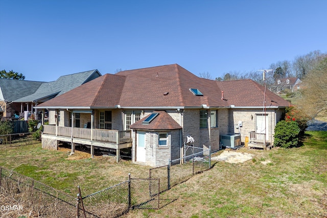 back of property featuring a gate, central AC, a fenced backyard, a yard, and brick siding