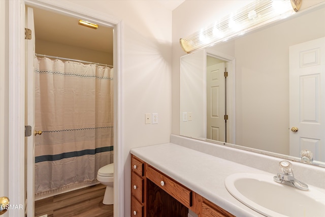 full bath featuring curtained shower, toilet, vanity, and wood finished floors