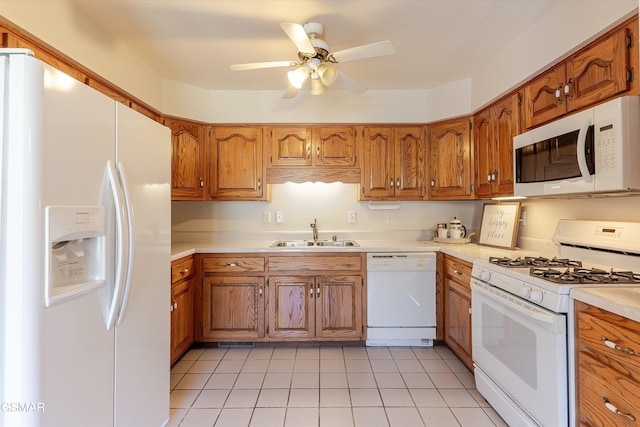 kitchen featuring white appliances, brown cabinets, and a sink