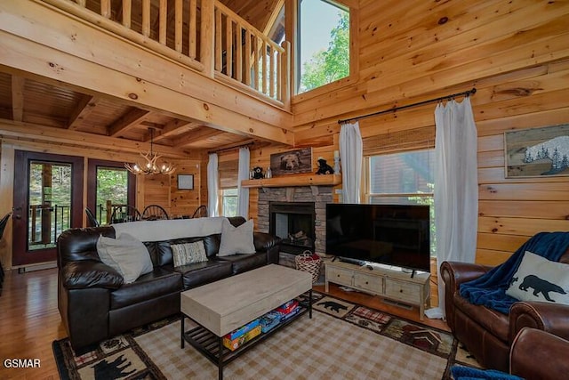 living area with wooden walls, a fireplace, an inviting chandelier, and wood finished floors