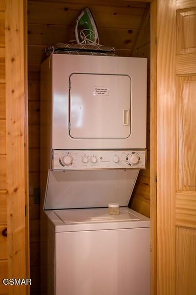 clothes washing area with stacked washer / dryer and wooden walls