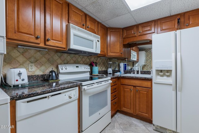 3215 N River Rd Ste 503, Pigeon Forge, TN 37863 - kitchen with a paneled ceiling, white appliances, dark stone countertops, light tile patterned floors, and tasteful backsplash