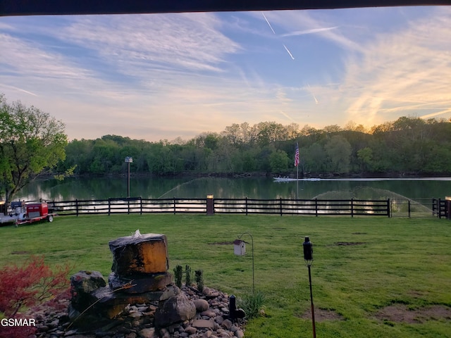 yard at dusk featuring a water view