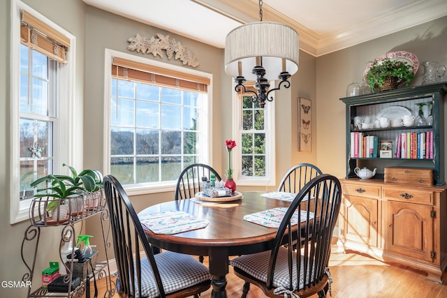 dining room with wood-type flooring, a wealth of natural light, a notable chandelier, and crown molding