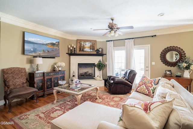 living room featuring wood-type flooring, ceiling fan, and crown molding