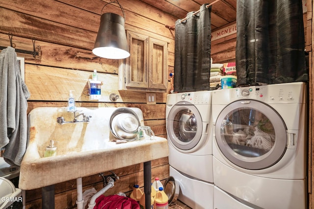 laundry area with washing machine and dryer, rustic walls, and wood walls