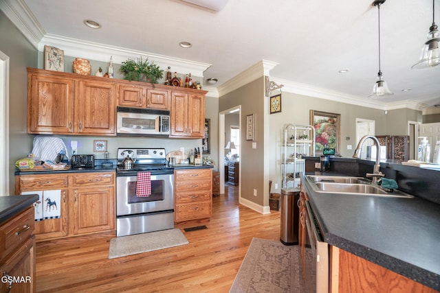 kitchen with sink, light hardwood / wood-style flooring, ornamental molding, appliances with stainless steel finishes, and pendant lighting