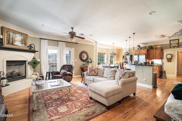 living room featuring a fireplace, crown molding, light hardwood / wood-style flooring, and ceiling fan