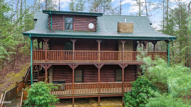 back of property featuring a shingled roof and log exterior