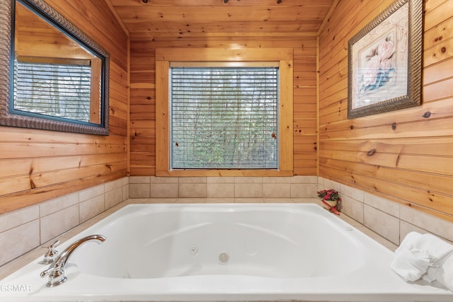 bathroom featuring wood walls, a wealth of natural light, and a jetted tub