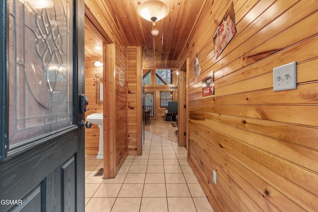hallway with wooden ceiling, light tile patterned floors, and wooden walls