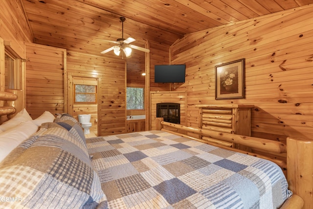 carpeted bedroom with wooden ceiling, ensuite bath, vaulted ceiling, wood walls, and a glass covered fireplace