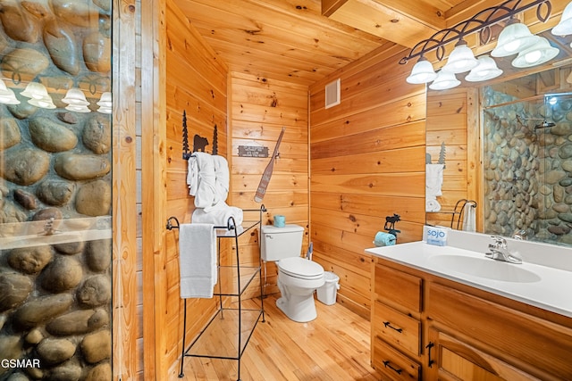 bathroom featuring vanity, wood walls, wooden ceiling, hardwood / wood-style flooring, and toilet