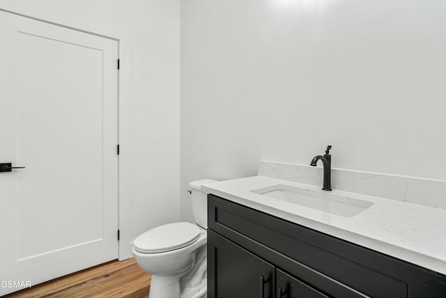 bathroom with toilet, wood-type flooring, and vanity