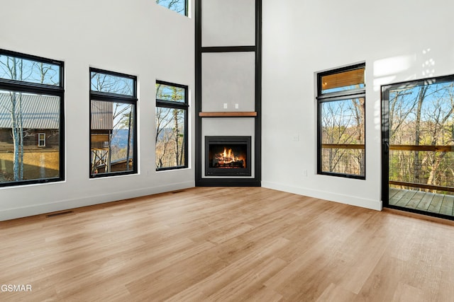 unfurnished living room with a towering ceiling and light hardwood / wood-style flooring