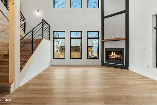 unfurnished living room featuring a towering ceiling and light wood-type flooring