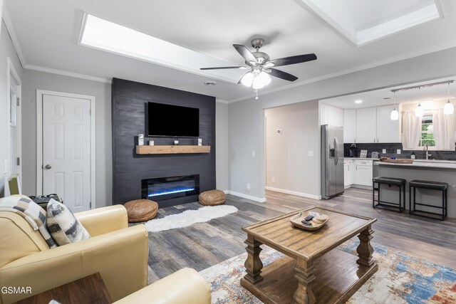 2887 Pine Haven Dr, Sevierville, TN 37862 - living room with dark wood-style floors, ceiling fan, baseboards, a large fireplace, and ornamental molding
