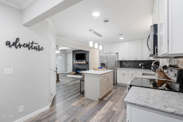 2887 Pine Haven Dr, Sevierville, TN 37862 - kitchen with appliances with stainless steel finishes, a kitchen island, a kitchen breakfast bar, crown molding, and decorative backsplash
