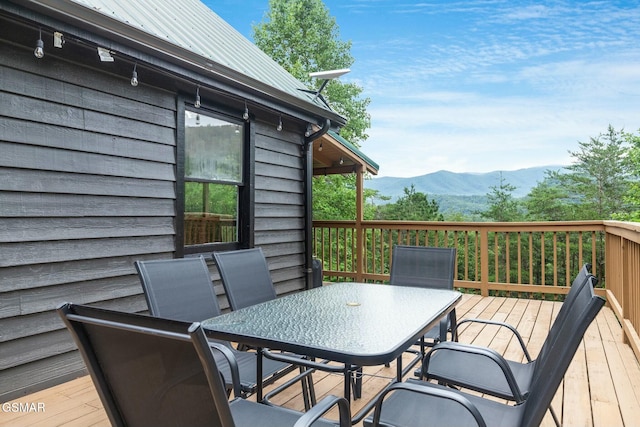 wooden terrace with outdoor dining area and a mountain view