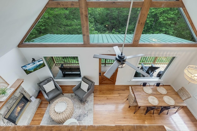 living room with ceiling fan, wood finished floors, a glass covered fireplace, and a wealth of natural light