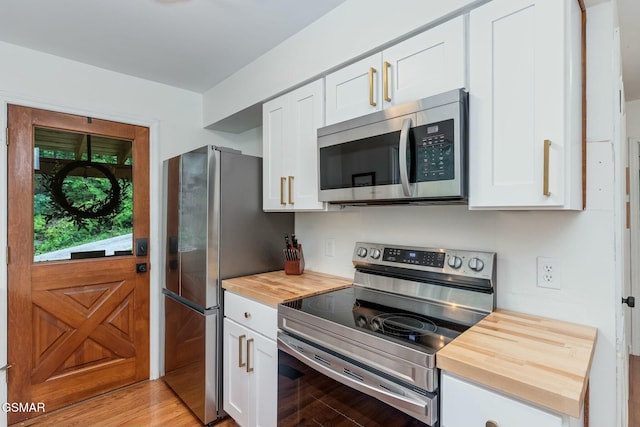 kitchen featuring white cabinets, light wood-type flooring, stainless steel appliances, and wooden counters