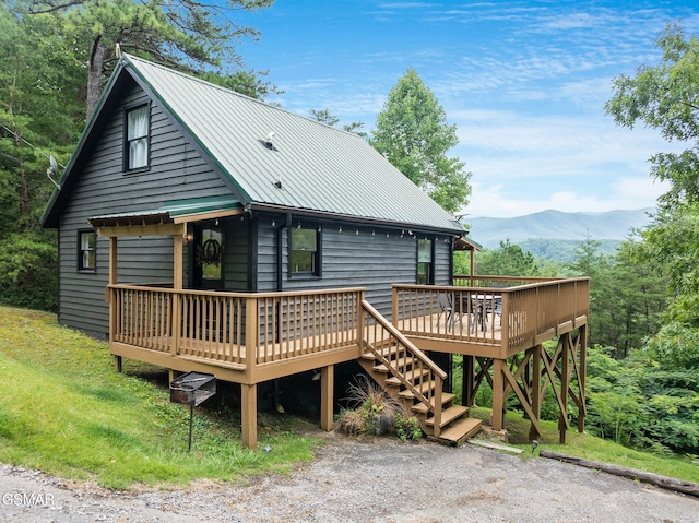 rear view of property featuring a deck with mountain view and metal roof