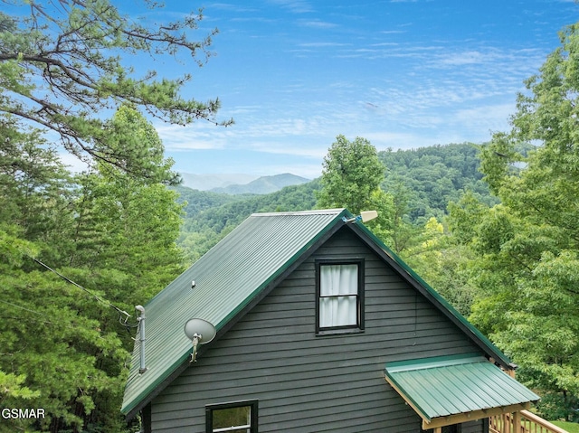 view of home's exterior with metal roof, a mountain view, and a forest view