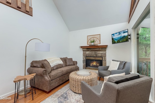 living area with high vaulted ceiling, a fireplace, baseboards, and wood finished floors