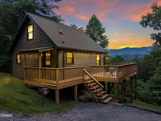 back of property at dusk featuring metal roof and a deck with mountain view