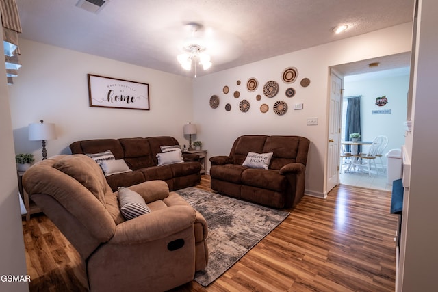 living area with visible vents, wood finished floors, and a ceiling fan